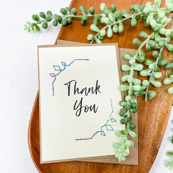 Greeting card with &#39;Thank You&#39; text on a wooden tray with greenery